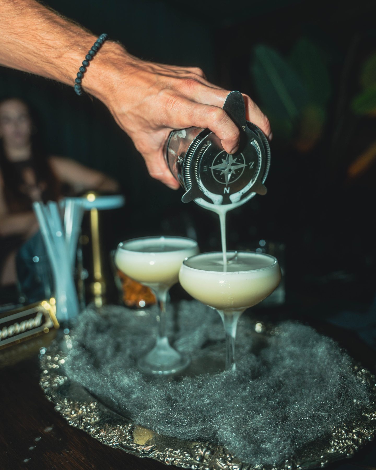 Compass-engraved shaker pouring a cocktail